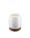White ceramic candle by Alessi in an egg-shaped holder, resting on a round brown wooden coaster with engraved patterns.