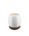 White ceramic candle by Alessi, with light yellow wax on a dark brown coaster with carved leaf patterns.