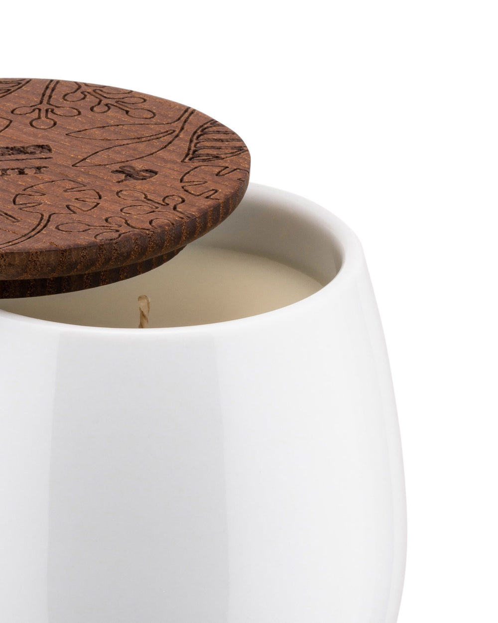 White ceramic candle by Alessi with a dark wooden lid featuring engraved leaf patterns, partially open to show the wick.