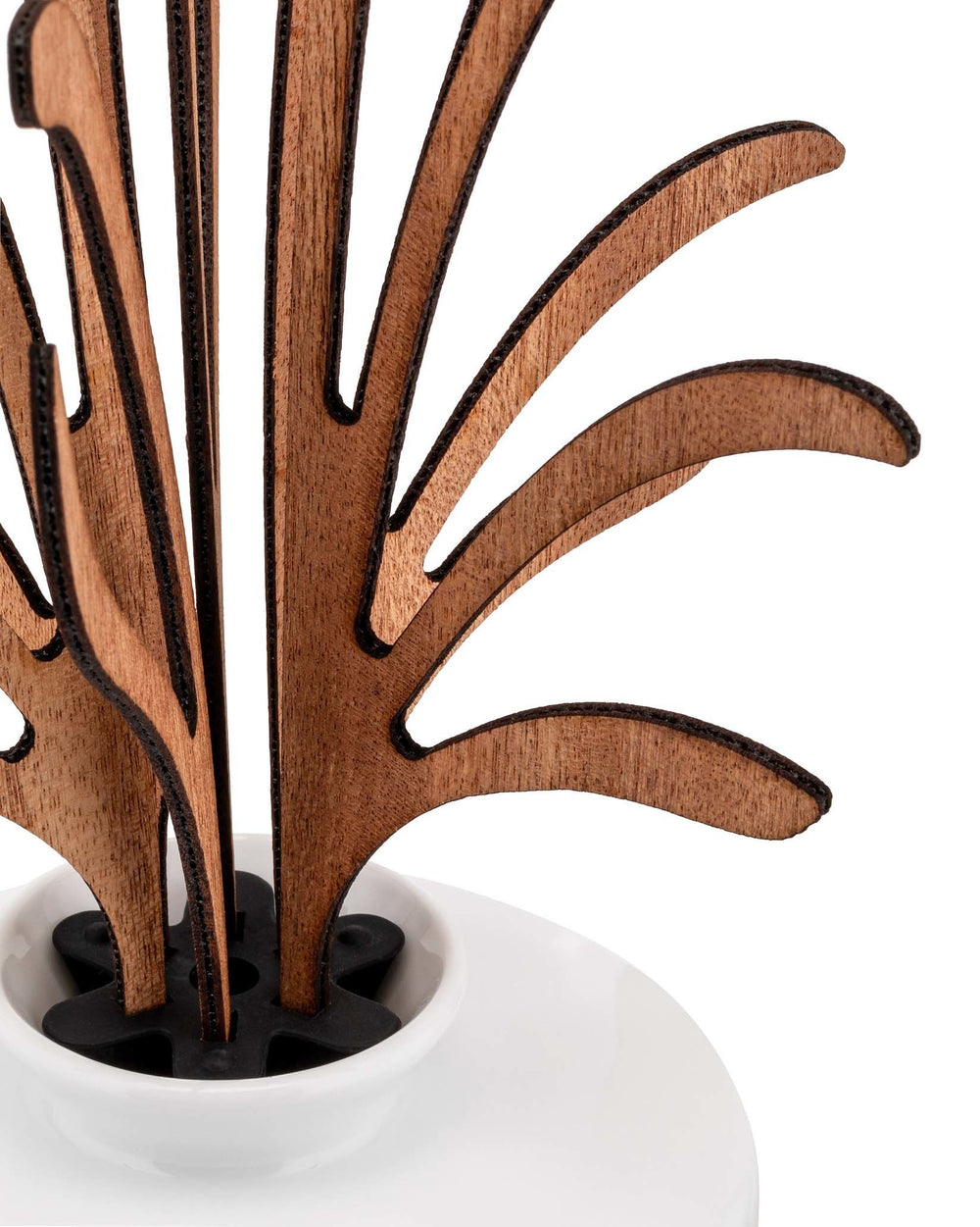 Brown wooden incense diffuser by Alessi with stylized leaf-like elements in a black holder and white ceramic bowl, close-up.