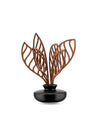 Modern decorative diffuser by Alessi featuring a matte black base and brown abstract wooden leaves.