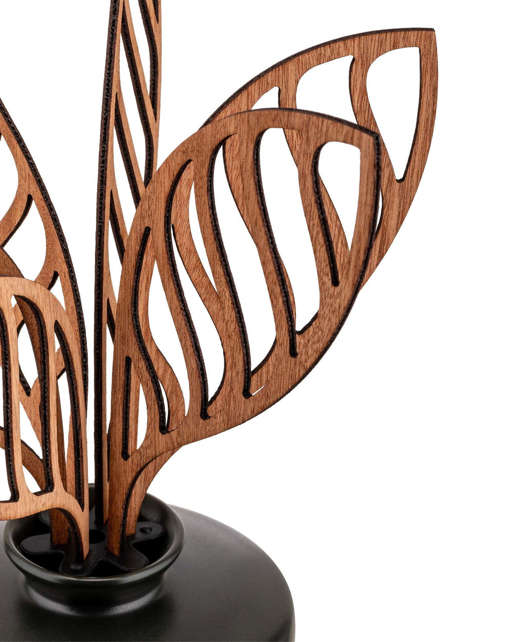 Wooden decorative diffuser with intricate laser-cut leaves by Alessi, in a dark grey ceramic base, close-up view.