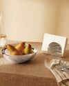 Silver-toned metal napkin holder by Alessi featuring a wavy, ribbed design, holding white napkins.