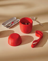 Red Food à porter portable food container by Alessi, open with its lid, a cutlery case, and a silicone strap.