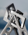Silver-grey metal occasional object by Alessi, with 'ALESSI' etched and interlocking textured geometric shapes.