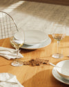 White Mami XL bowl and plate by Alessi, stacked on a polished wooden table.