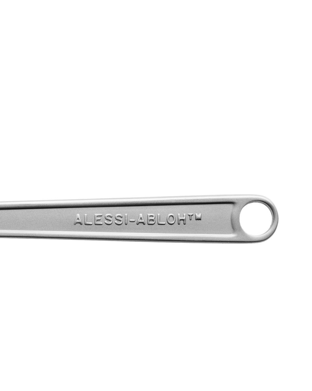 Silver metal utensil or tool part by Alessi, with engraved ALESSI-ABLOH™ logo and hanging hole, close-up.