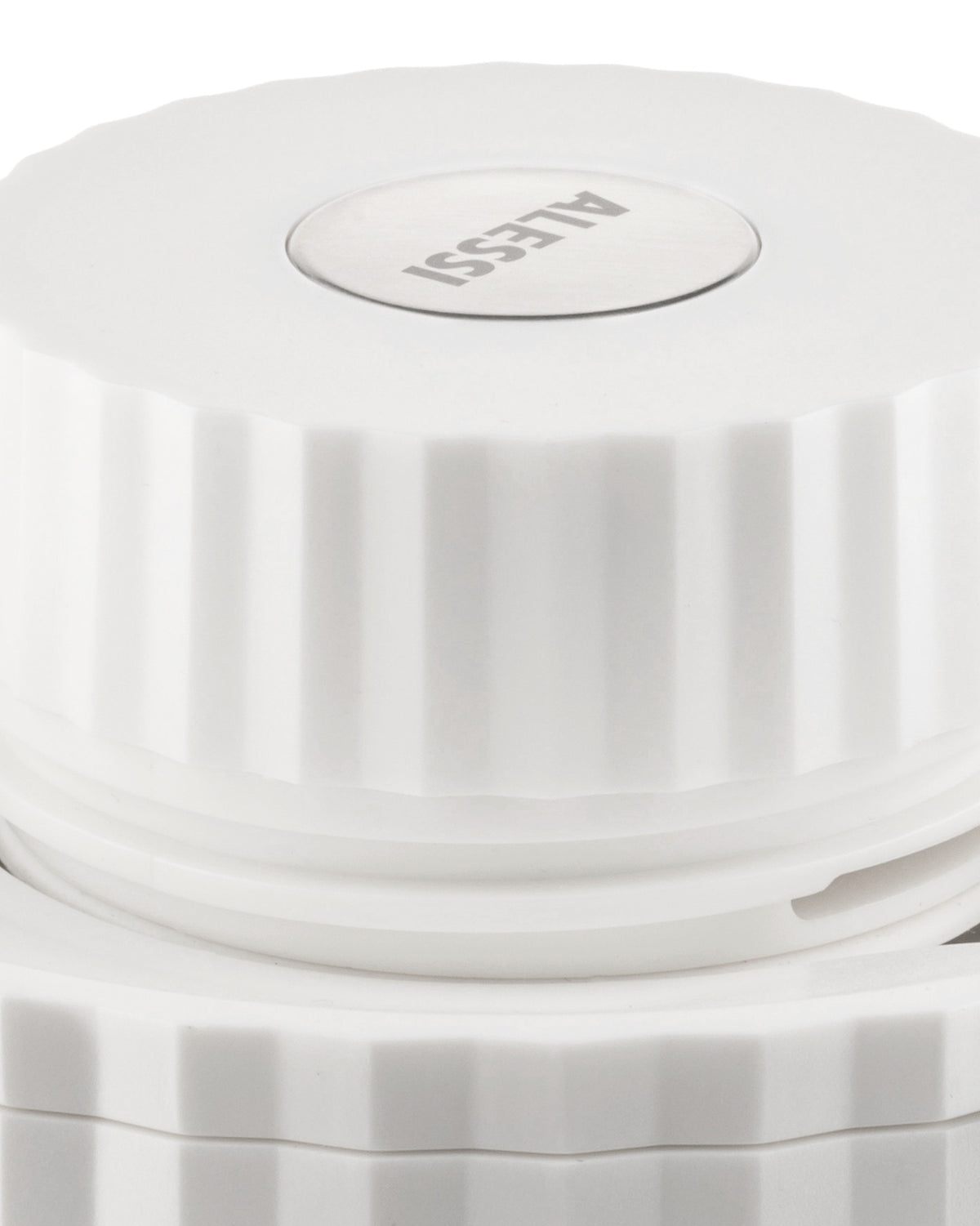 White pleated lid by Alessi with a circular metal logo, shown from an elevated angle.