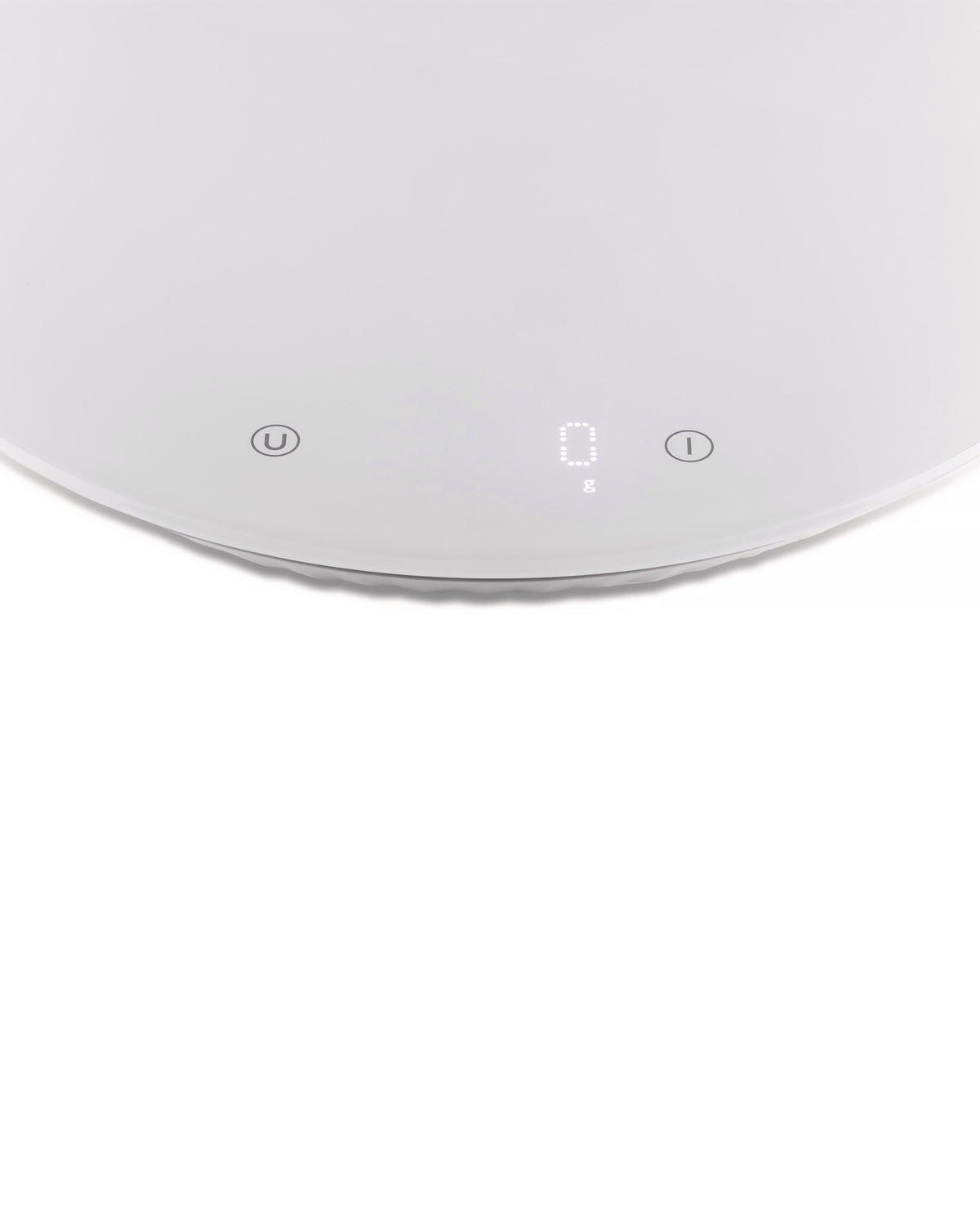 White digital kitchen scale by Alessi, displaying '0 g', with 'U' and 'I' symbols on a round, smooth surface, top-down view.